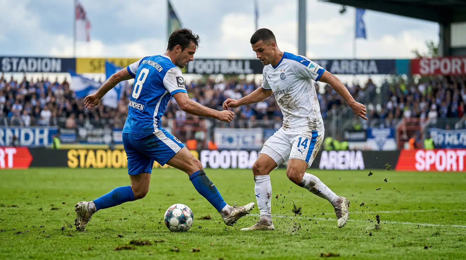 Fußballspieler im Zweikampf auf grünem Rasen während eines Ligaspiels