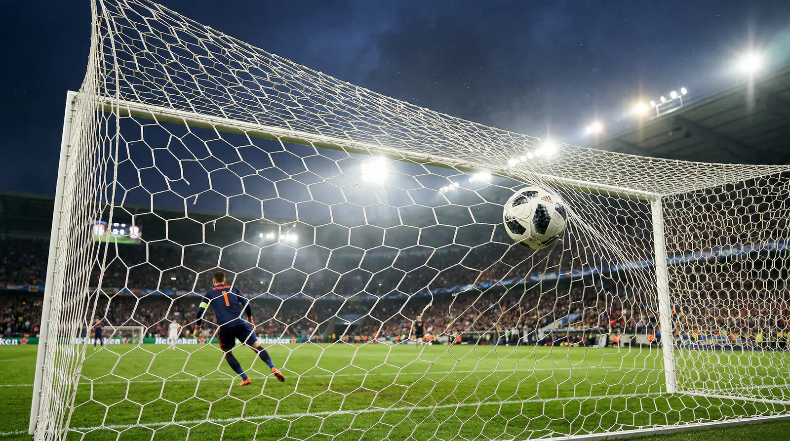 Fußball fliegt ins Tornetz bei einem Schuss im Flutlicht-Stadion